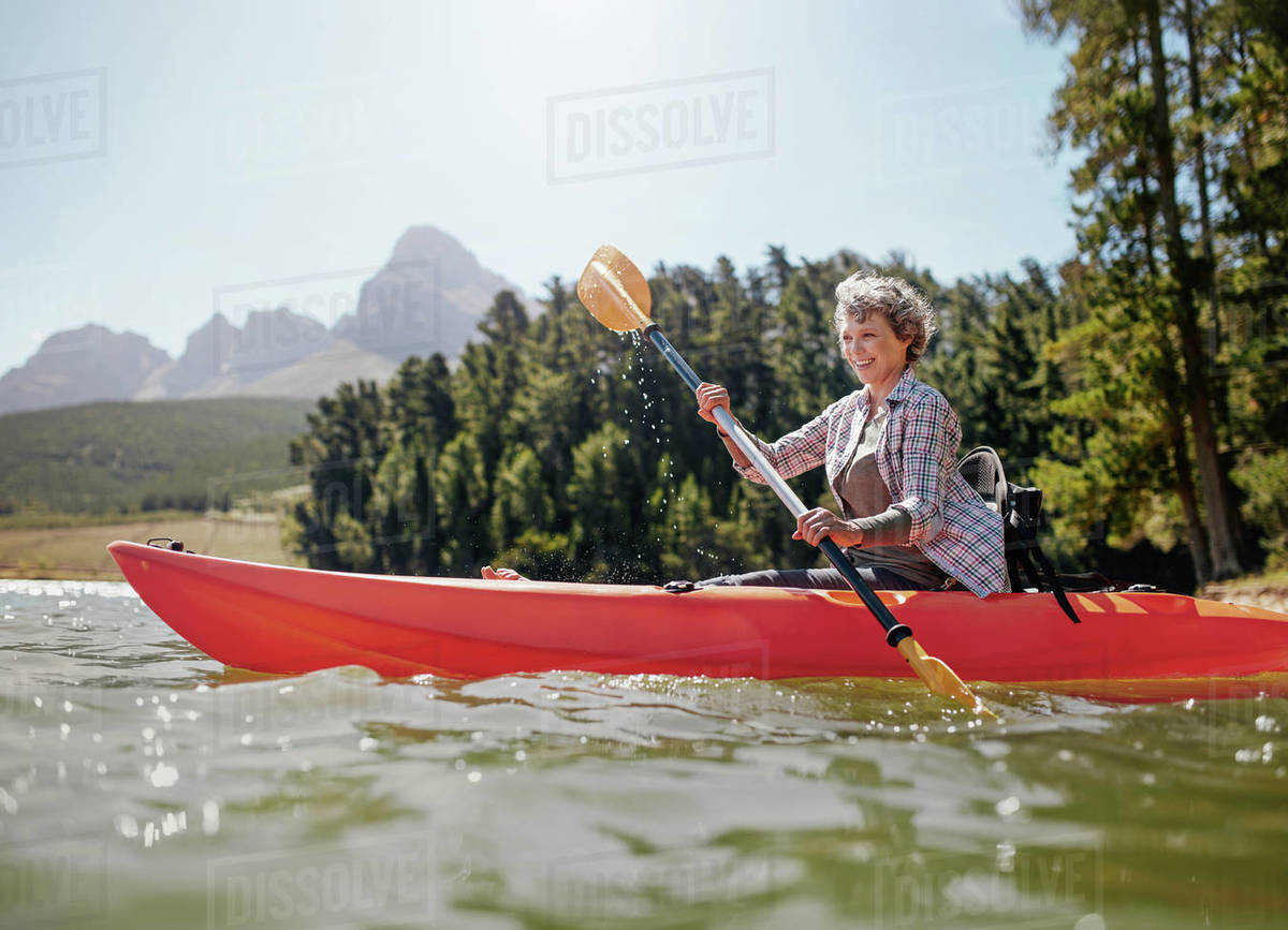 Shot of senior woman kayaking on lake on a summer day. Mature woman