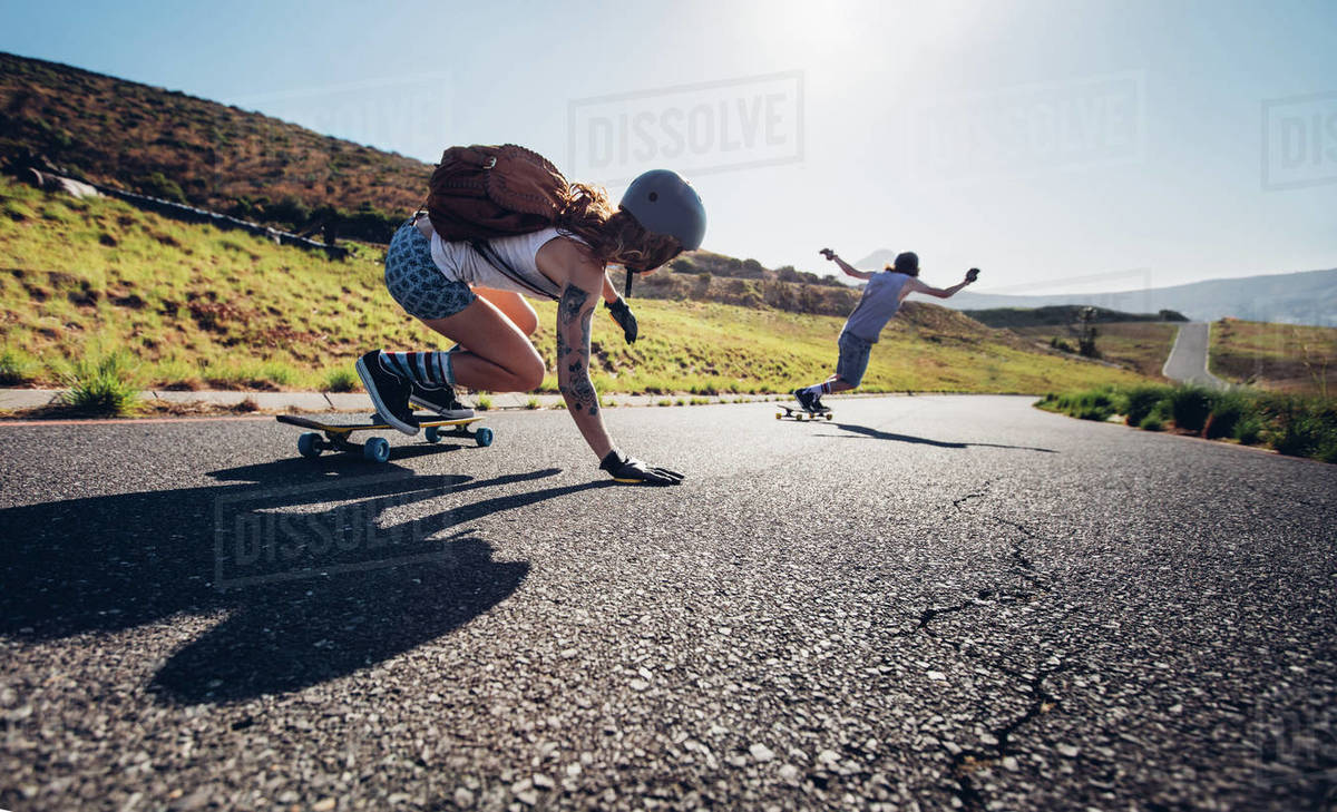 Young people skateboarding outdoors on the road. Young man and woman practicing skating on a rural road. Royalty-free stock photo