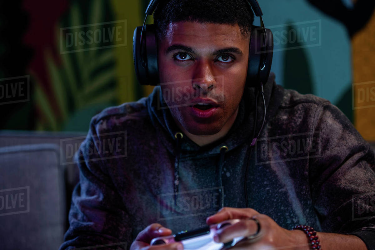 Closeup of male AfricanAmerican gamer wearing headphones while playing