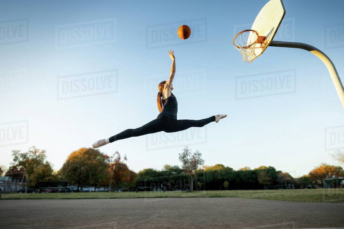 Female ballet dancer shooting baskets on an outdoor Basketball court