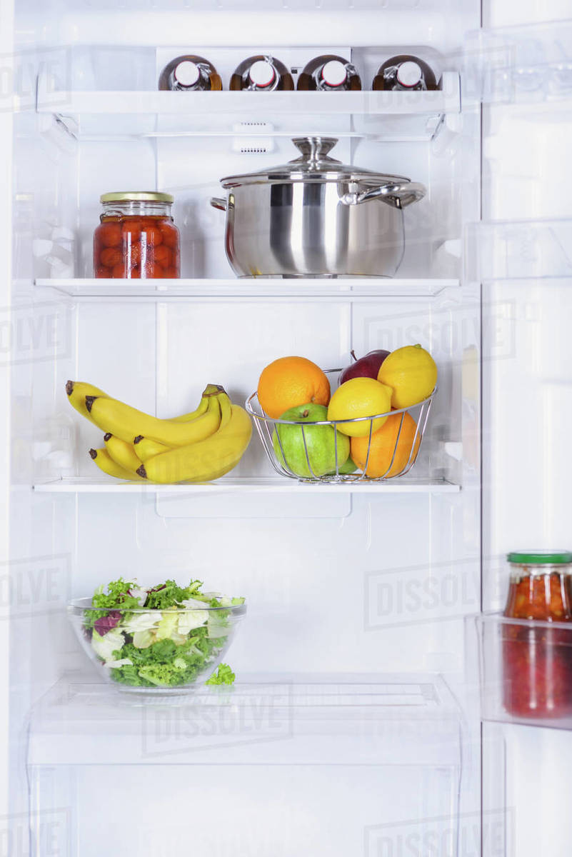 Ripe fruits, salad, pan and preserved tomatoes in fridge Stock Photo Dissolve