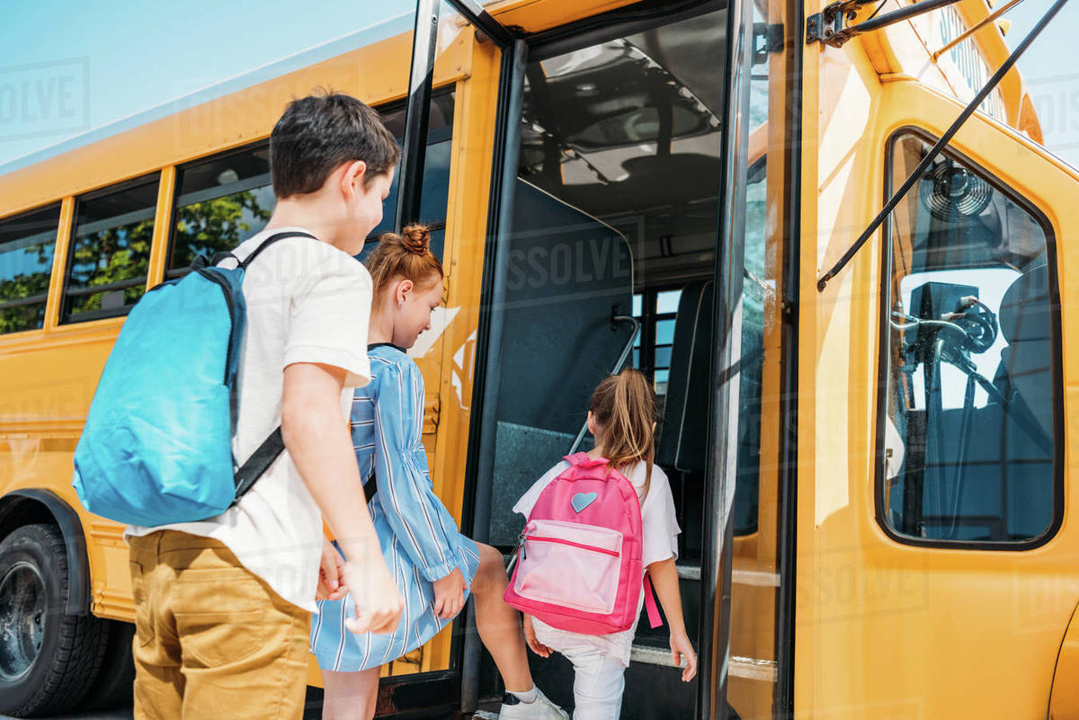 rear view of pupils with backpacks entering school bus Stock Photo