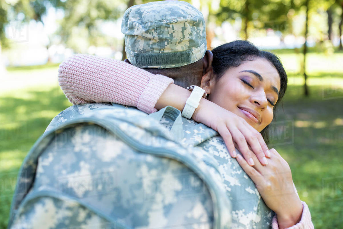 African american soldier in military uniform hugging happy girlfriend in  park - Royalty-free Stock Photo | Dissolve