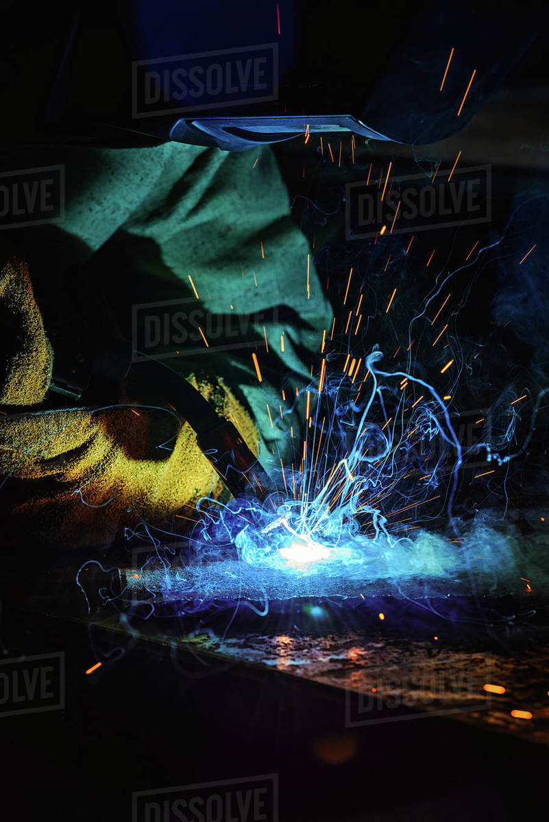 Focused welder in protection mask brazing metal at factory Stock