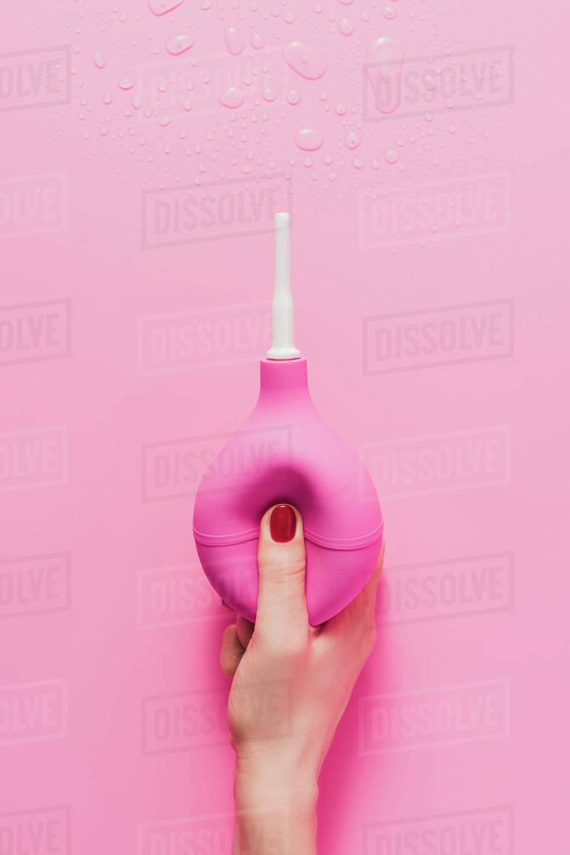 Cropped shot of woman holding douche on pink Stock Photo Dissolve