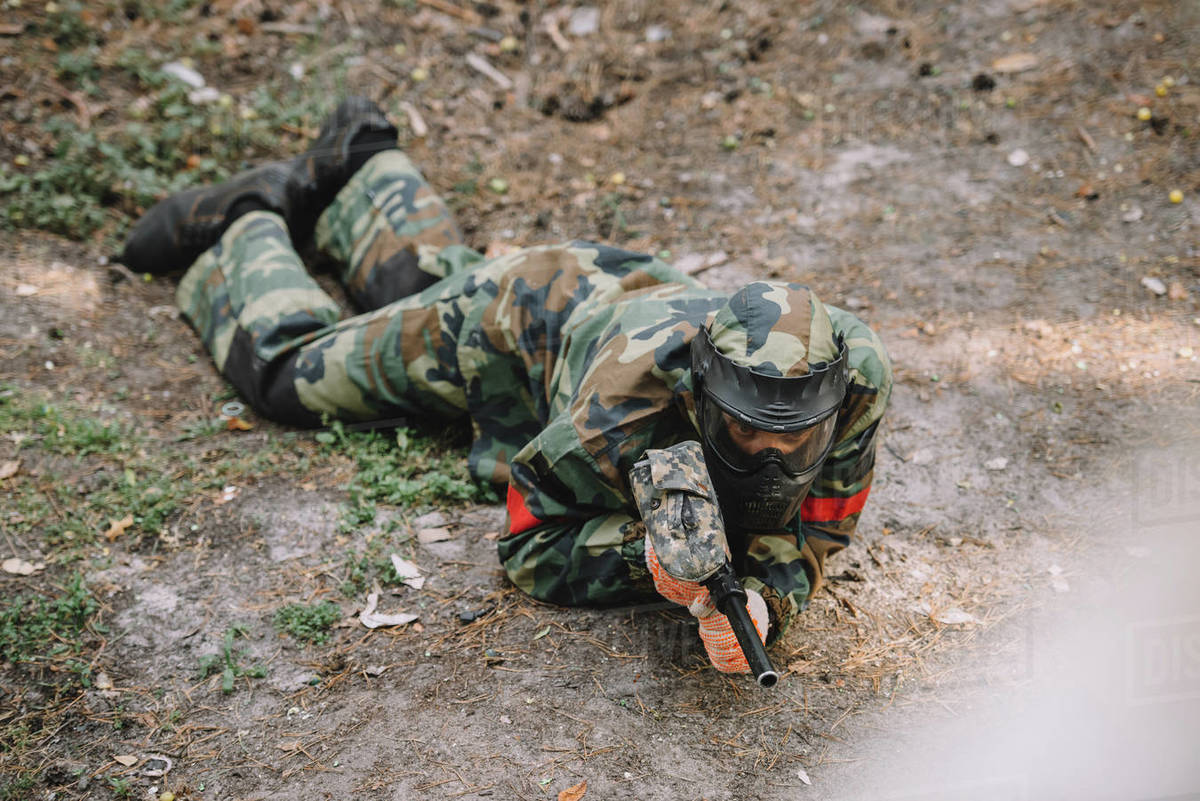 High angle view of male paintball player in goggle mask and camouflage
