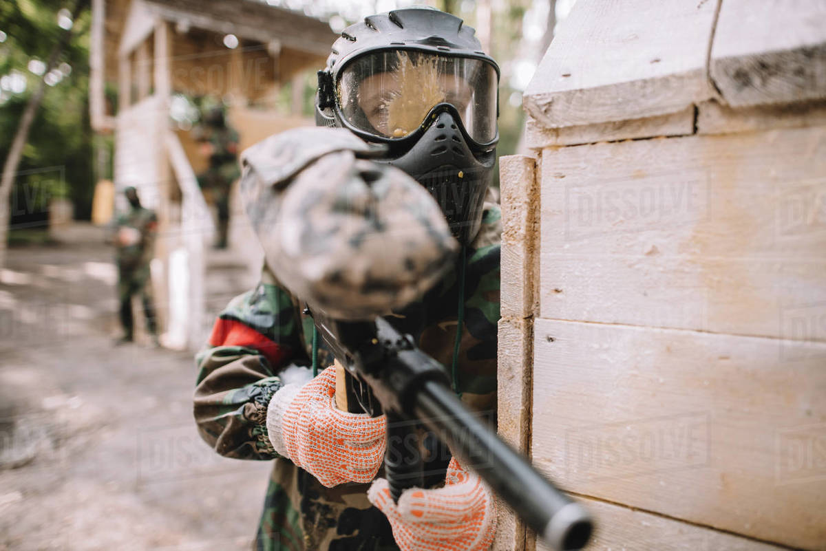 Selective focus of male paintballer in goggle mask covered by paintball