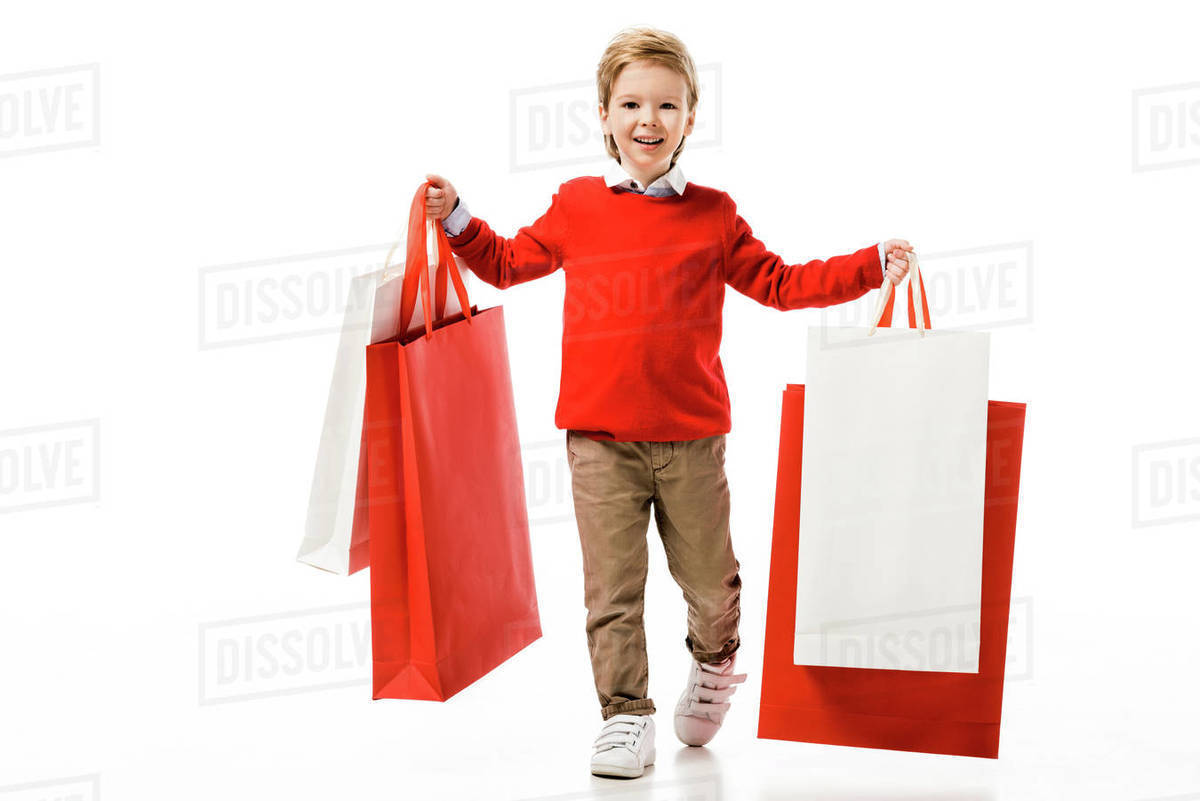 Happy little kid holding big shopping bags isolated on white