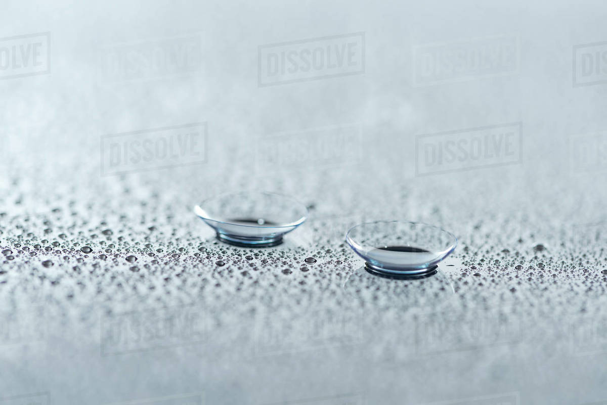Close up view of contact lenses on background with water drops Stock