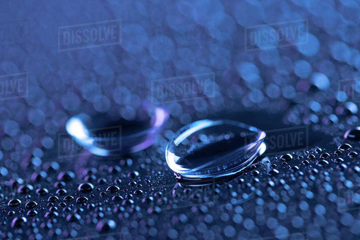 Selective focus of contact lenses and water drops on blue background