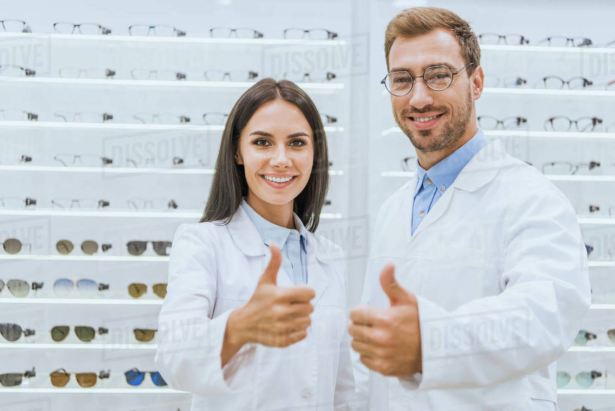 Professional doctors in white coats showing thumbs up in optics with