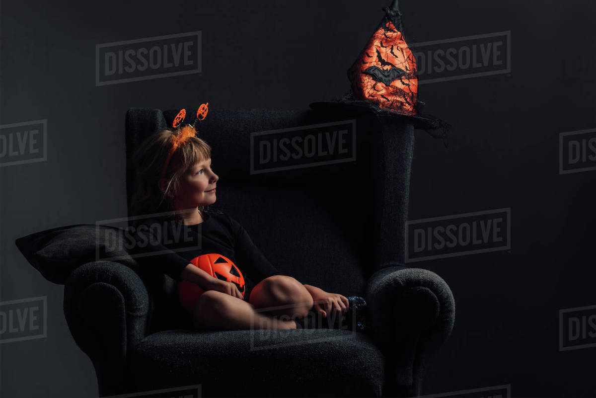 adorable kid in halloween costume resting in armchair at home Stock