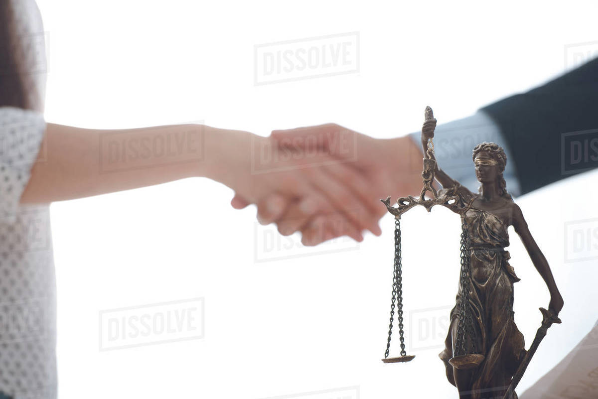 Closeup view of lady justice statue and lawyer with client blank