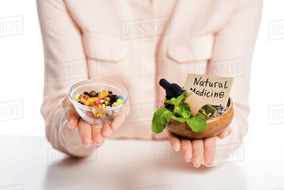 cropped image of woman holding bowls with natural medicine oil and pharmacological drugs