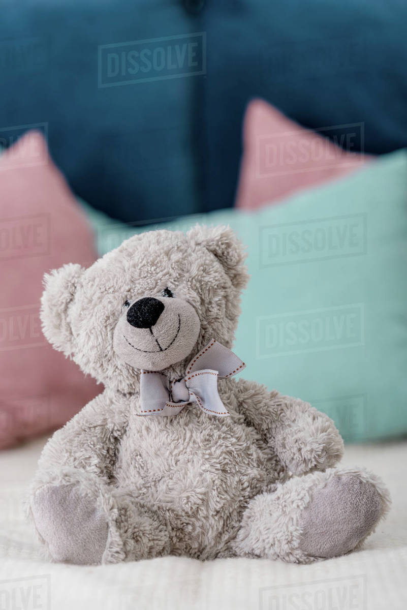 Close Up Vertical View Of Teddy Bear Sitting On The Bed With