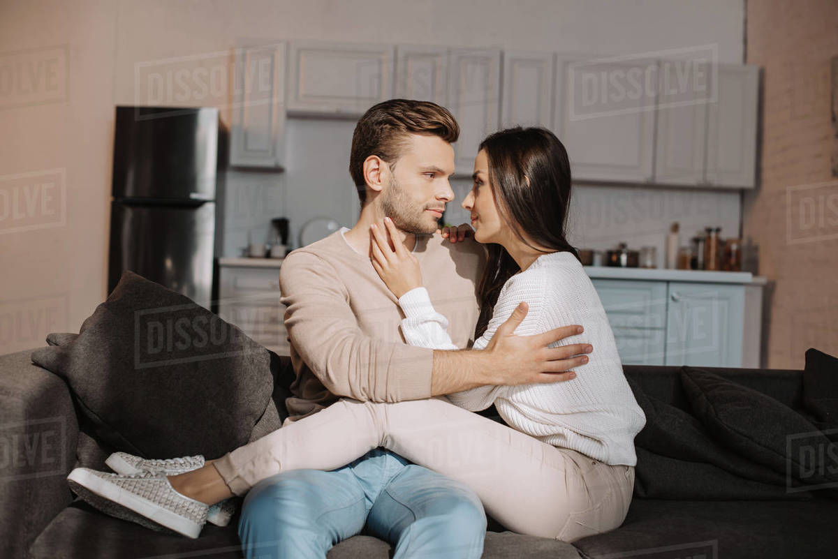 Romantic Young Couple Cuddling On Couch At Home Stock Photo