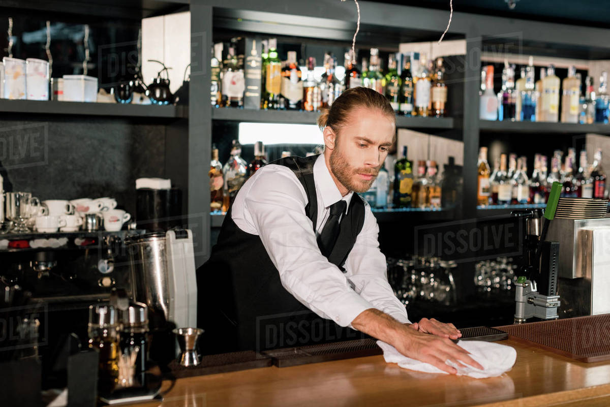 Bartender cleaning wooden bar counter with white napkin Stock Photo