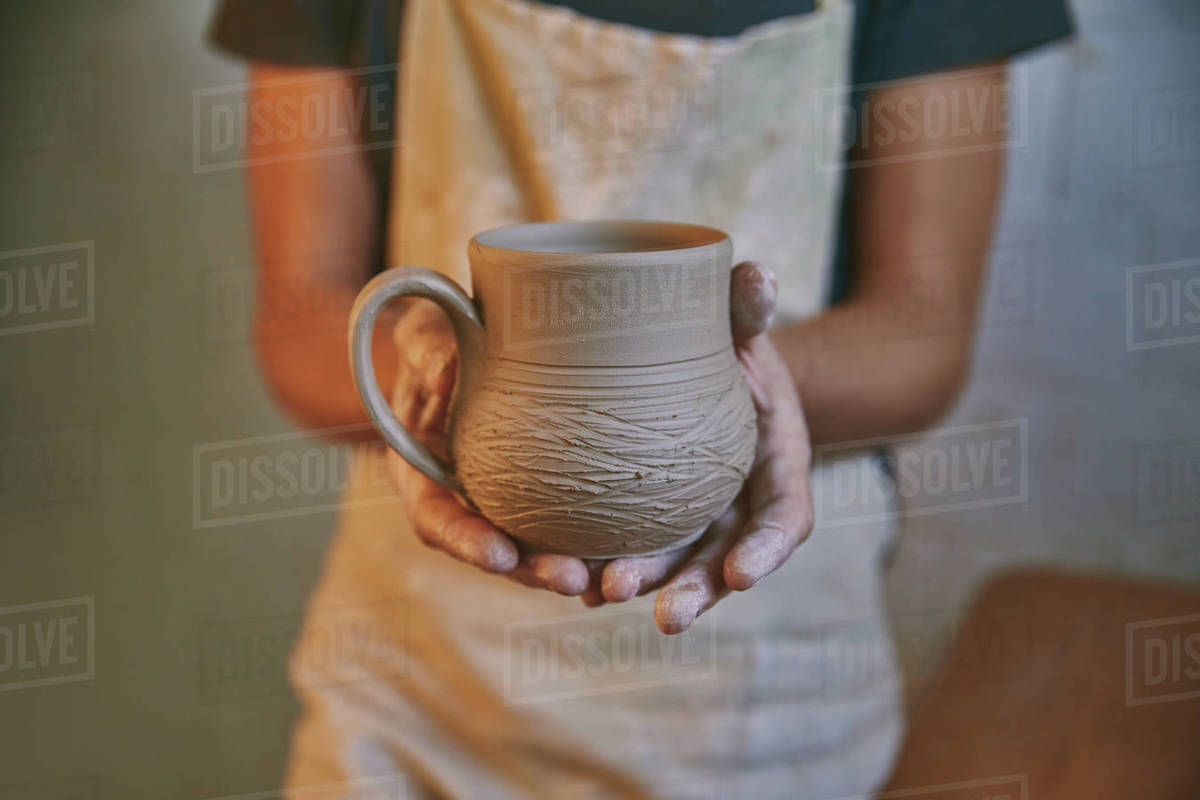 selective focus of man holding clay pot in pottery studio Stock Photo