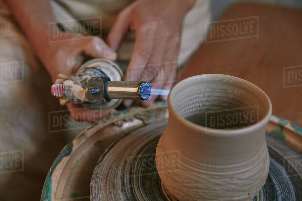 selective focus of male potter firing clay pot at pottery studio Stock Photo Dissolve