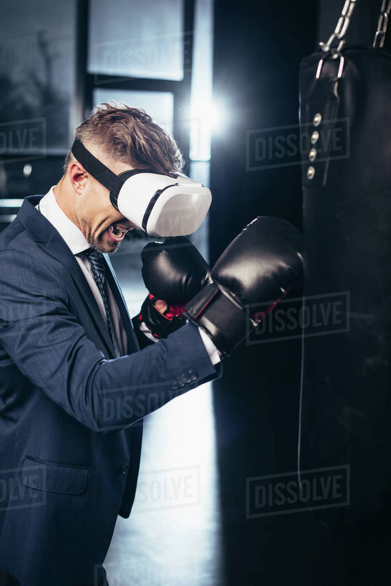 Businessman in suit and virtual reality headset boxing and