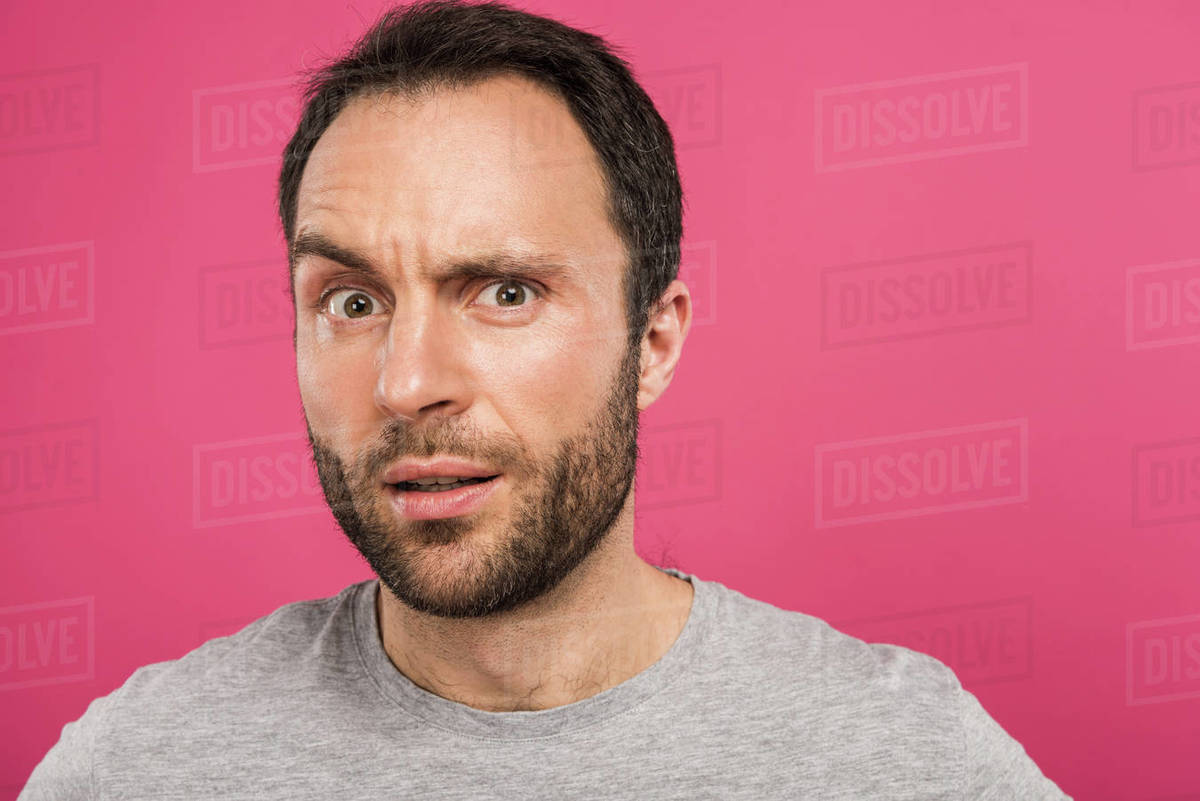 portrait of confused man looking at camera, isolated on pink - Stock ...