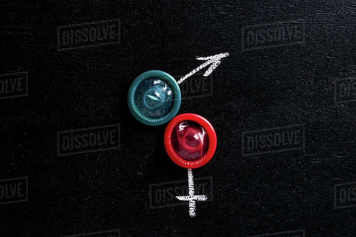 Top view of condoms with male and female signs on black background