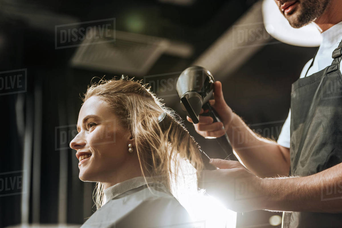 Low Angle View Of Hairstylist Combing And Drying Hair To Beautiful