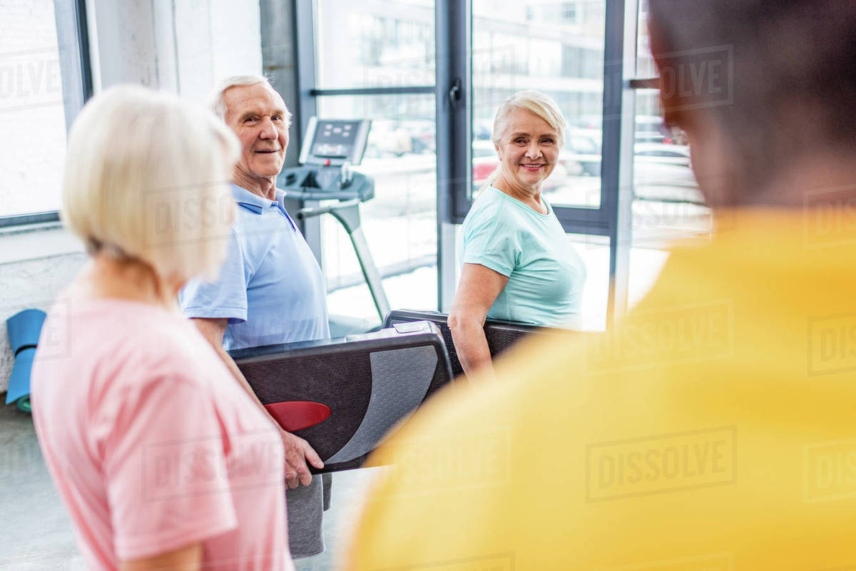Selective focus of senior sportspeople holding step platforms at gym