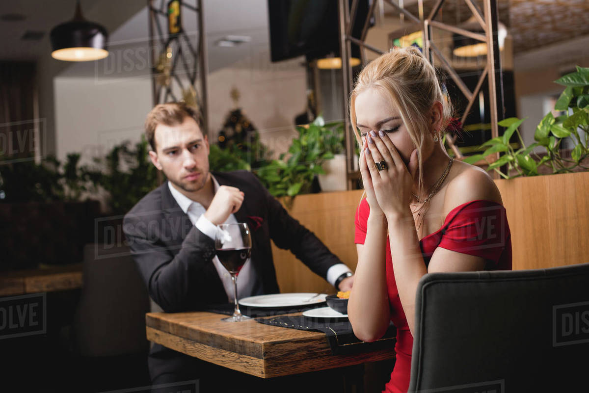 Selective focus of offended woman crying near boyfriend in restaurant