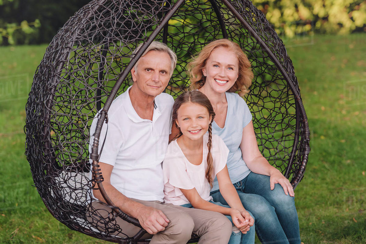 portrait of grandparents and smiling granddaughter looking at camera