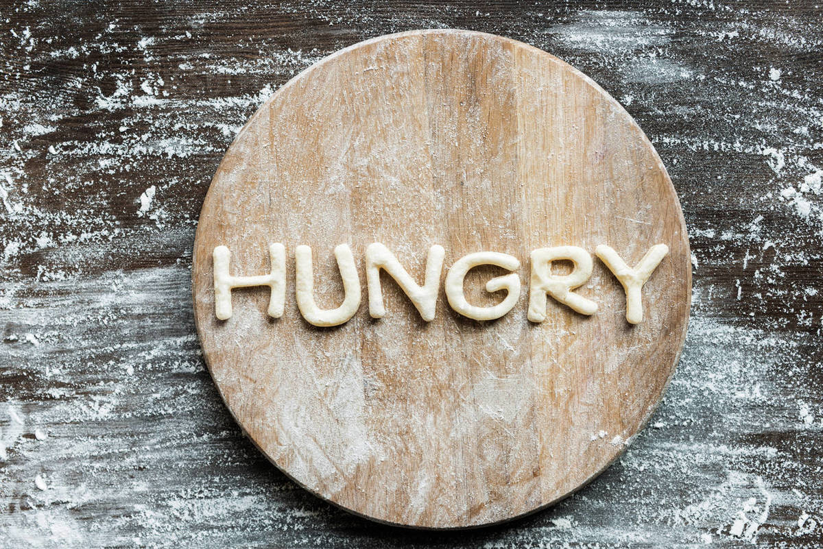 Top view of word hungry made from cookie dough with flour on wooden