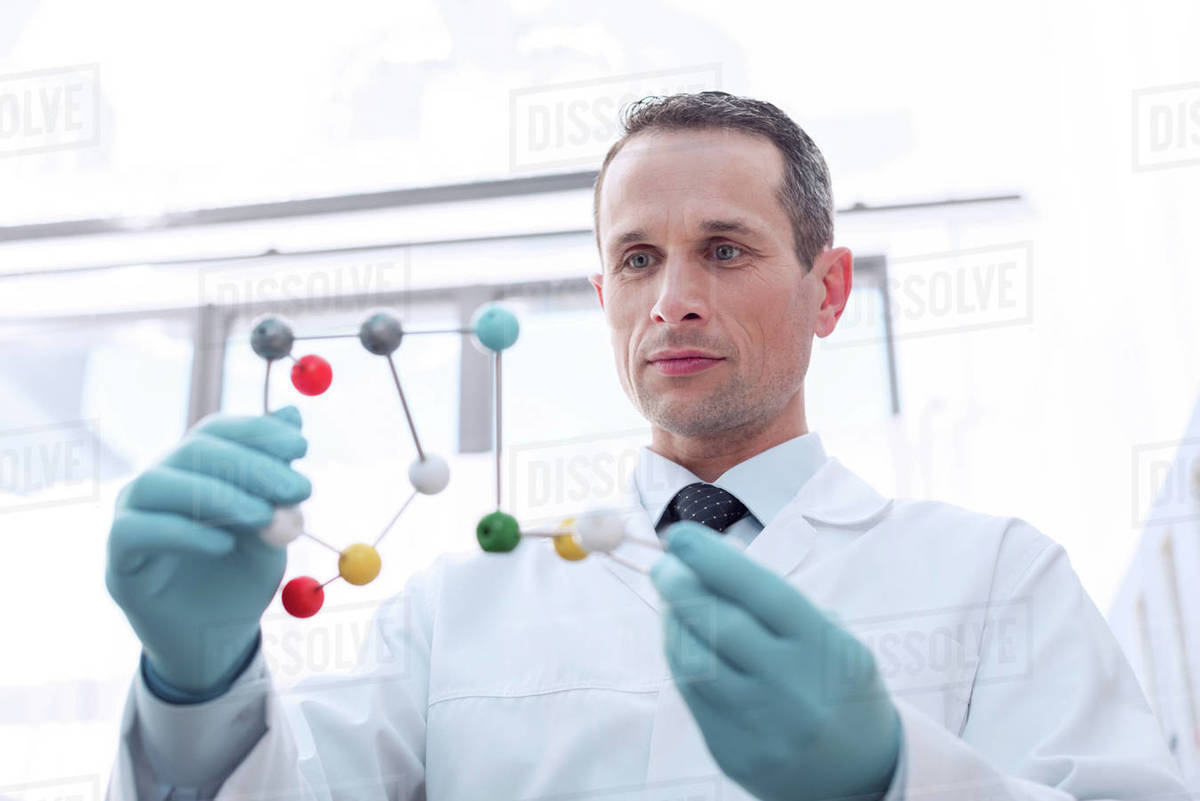 A medical worker in lab coat and latex gloves, examining a molecular