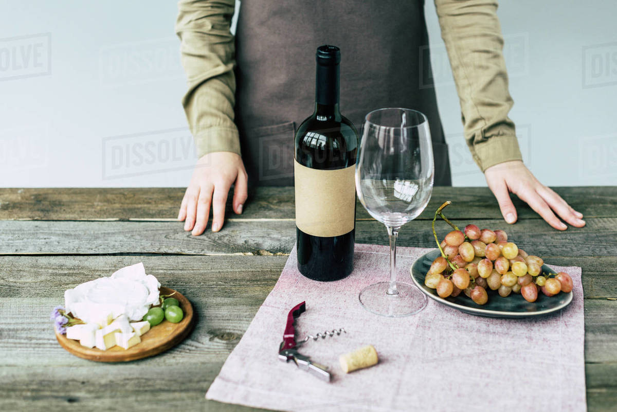Female sommelier standing near table with wine and food Stock Photo