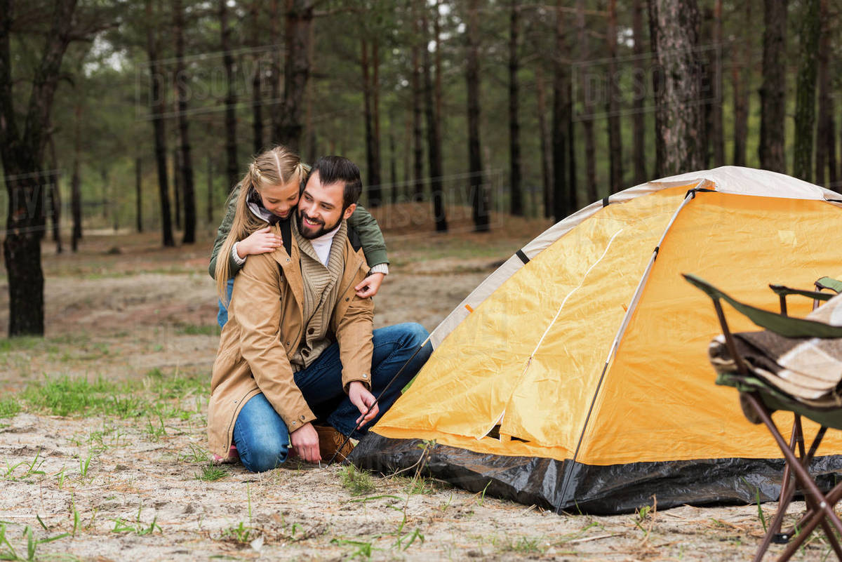 happy father and daughter installing tent for camping - Stock Photo