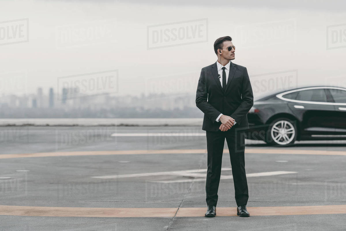 Serious bodyguard standing with sunglasses and security earpiece on