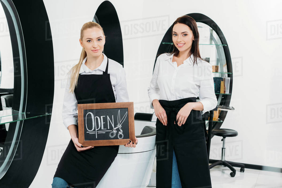 Two hairdressers with signboard open at hair salon Stock Photo Dissolve