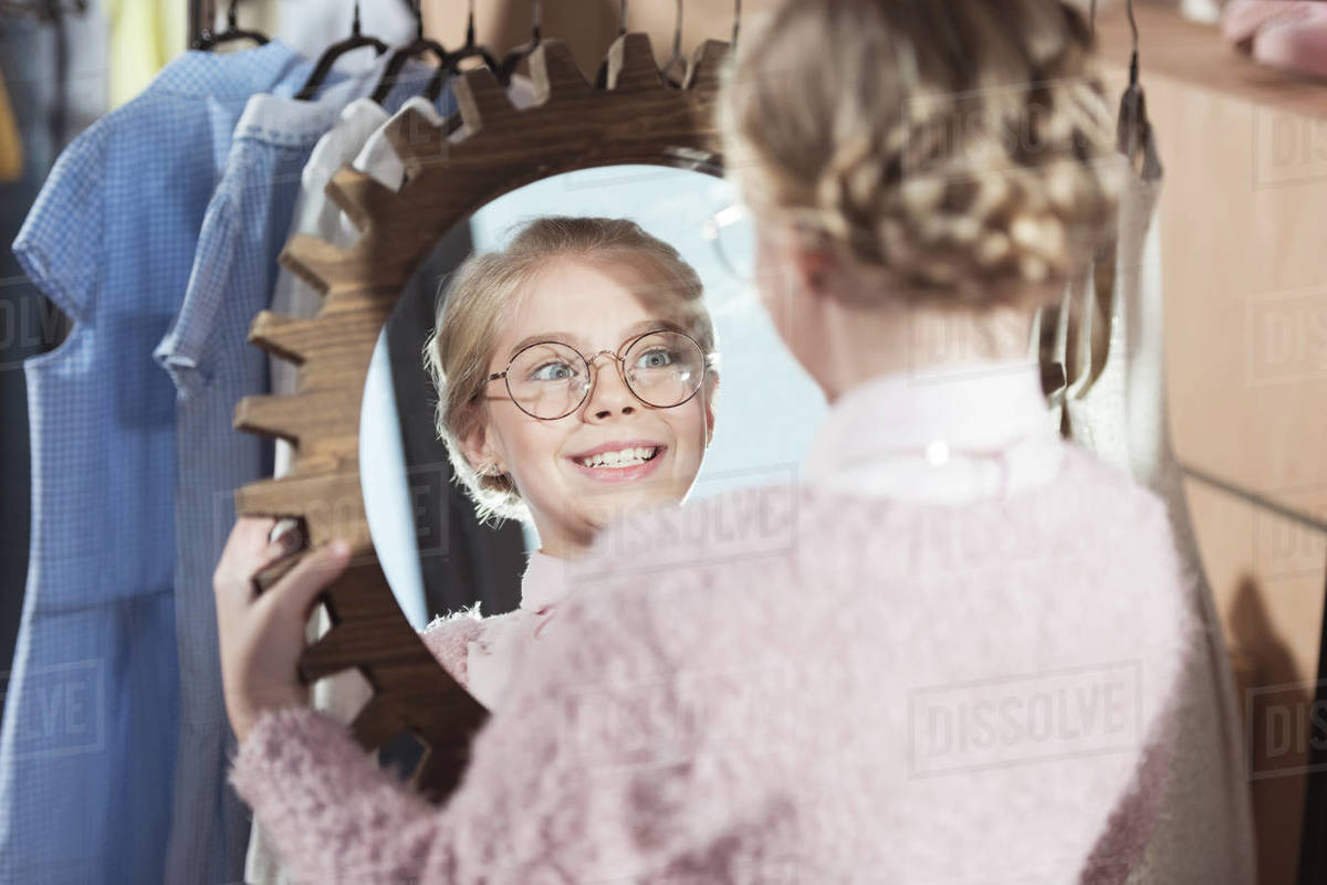 smiling child looking at mirror in her hands at store interior Stock