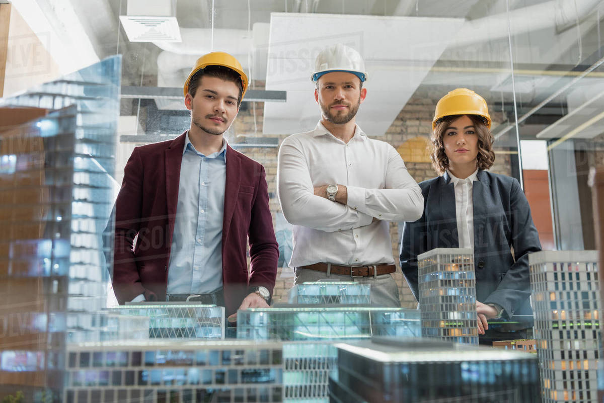 Team of architects in hard hats in front of miniature town model Royalty-free stock photo