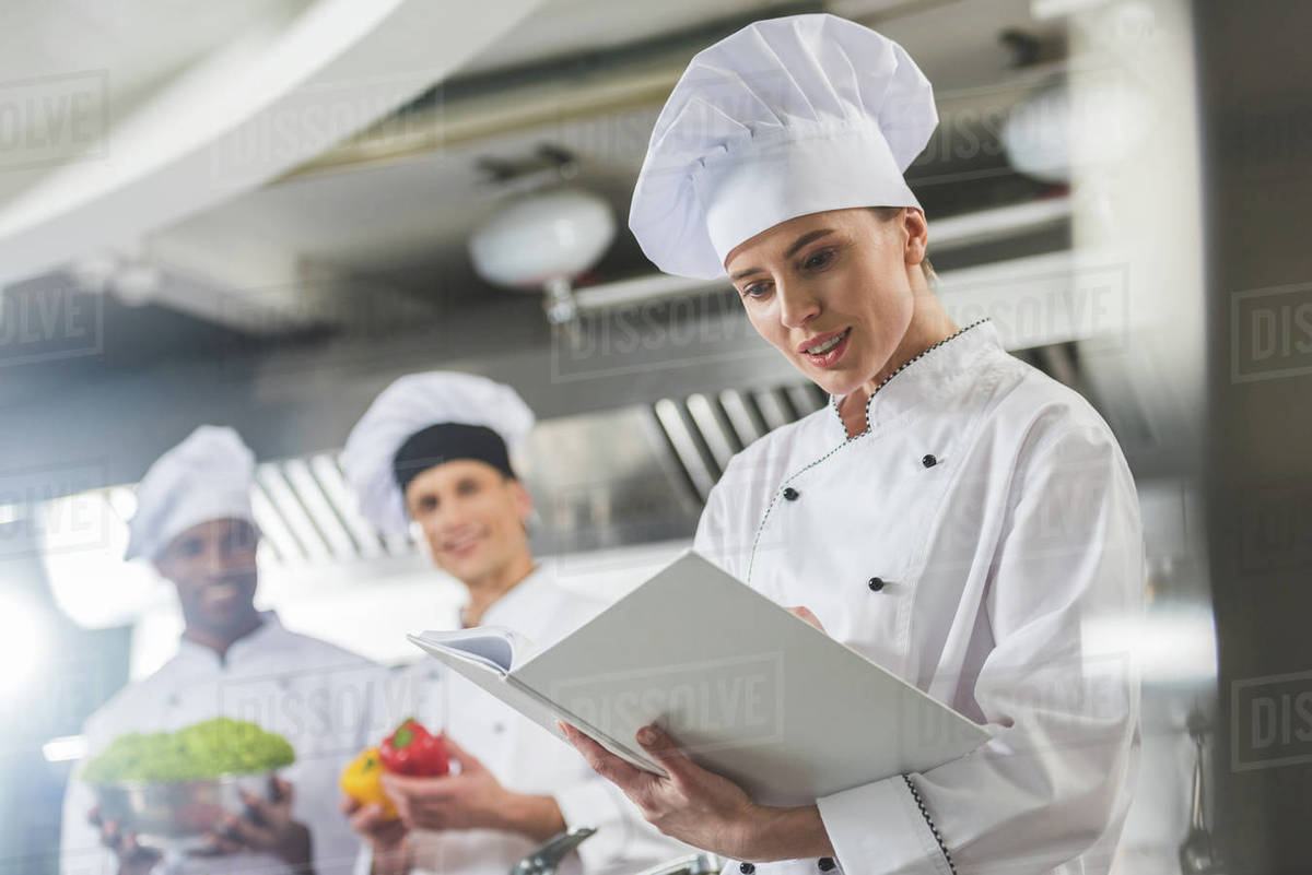 Attractive chef reading recipe at restaurant kitchen - Stock Photo -  Dissolve