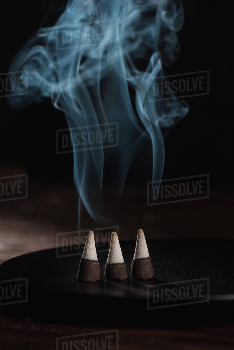 Three burning incense sticks with smoke on black Stock Photo Dissolve