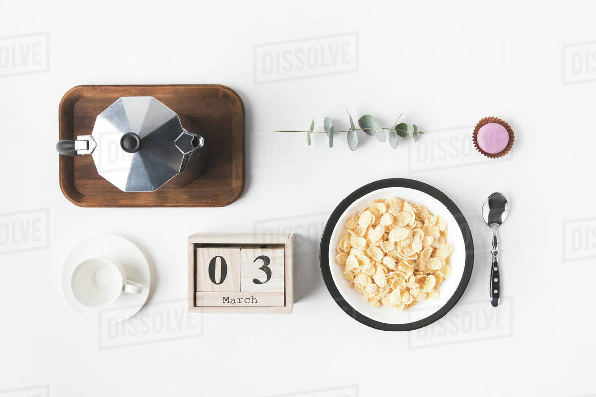 flat lay with corn flakes in bowl for breakfast, coffee maker and cup