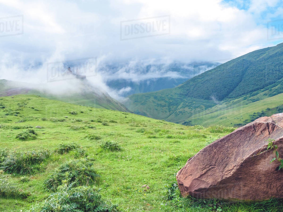 Beautiful idyllic landscape with mountains and ancient church in clouds ...