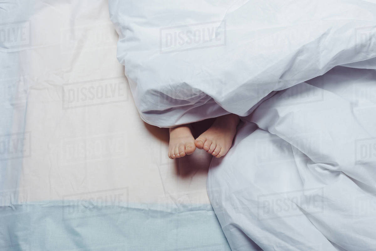 Cropped shot of child feet underneath blanket Stock Photo Dissolve
