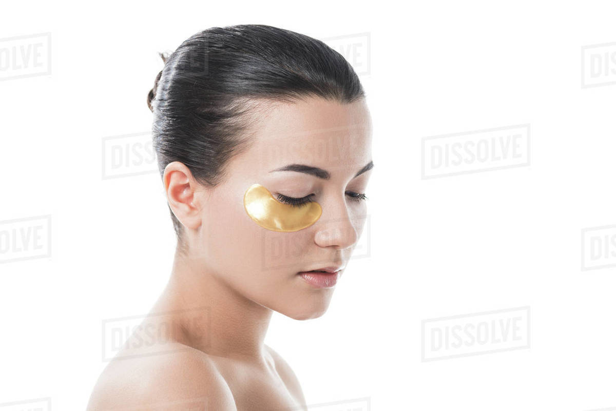 Beautiful girl with moisturizing under eye patch looking down isolated