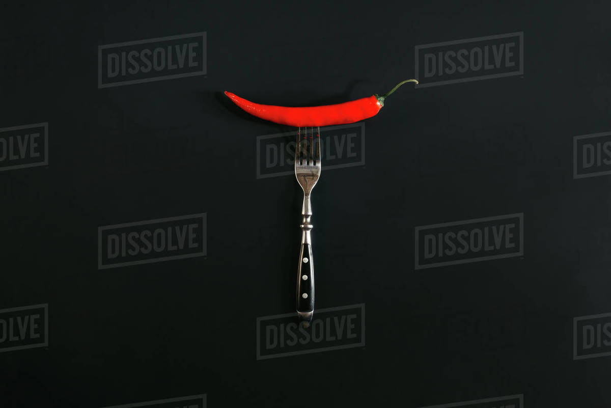 Red hot chili pepper on fork on black Stock Photo Dissolve