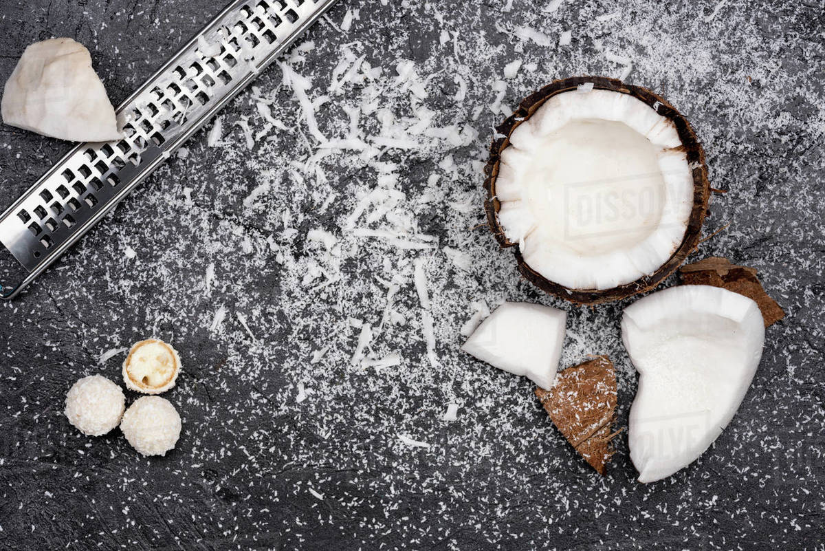 Top view of fresh broken coconut with shavings on black Stock Photo Dissolve