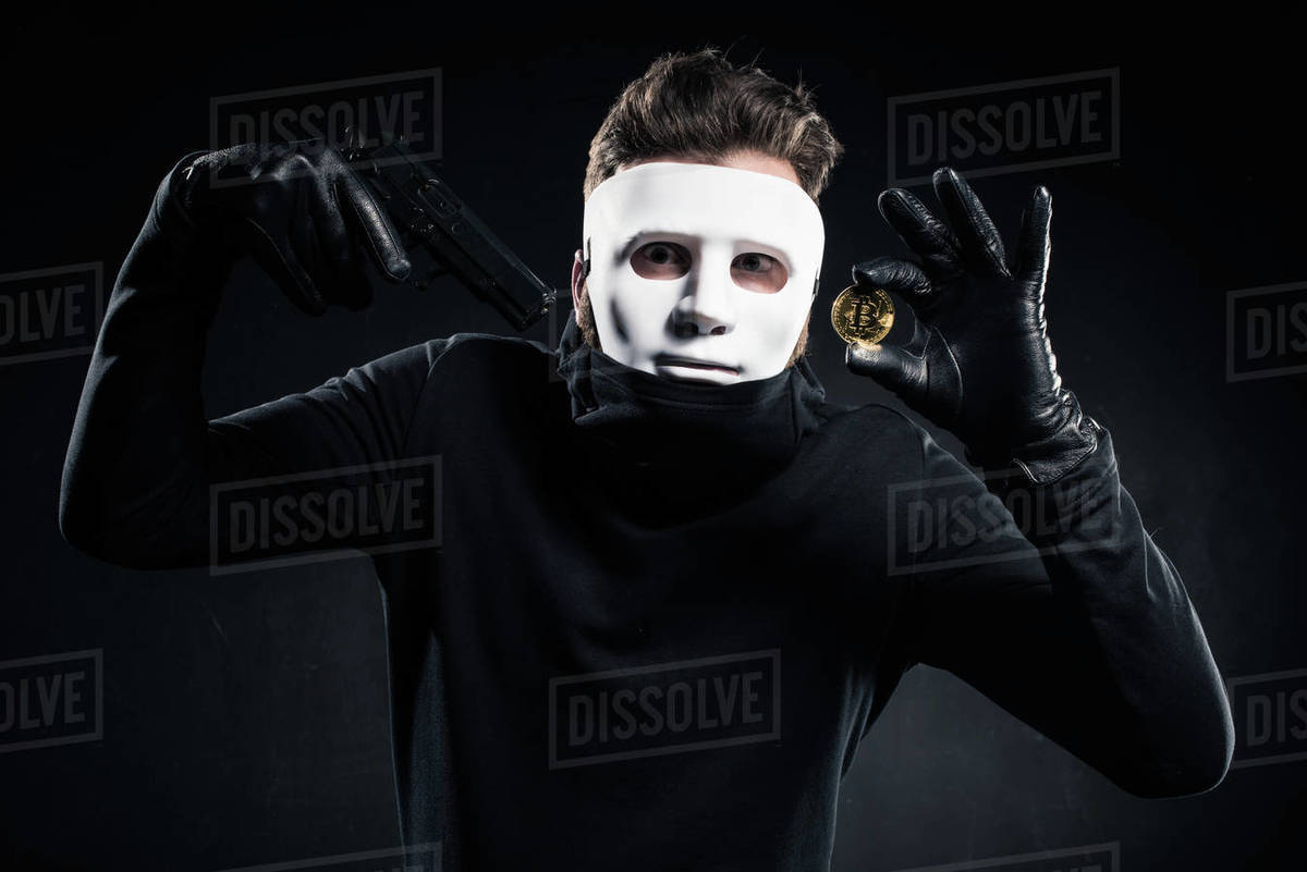 Man in white mask holding gun and golden bitcoin Stock Photo Dissolve