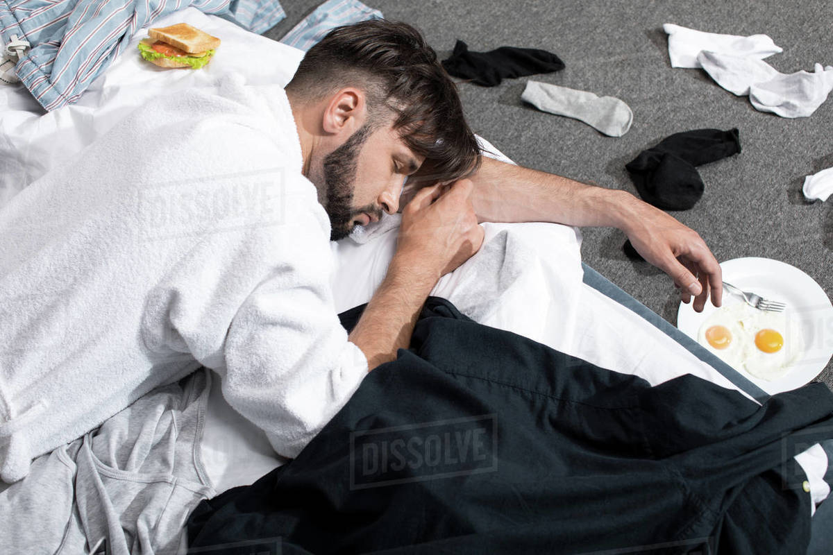 Tired young man in bathrobe sleeping on bed in morning Stock Photo