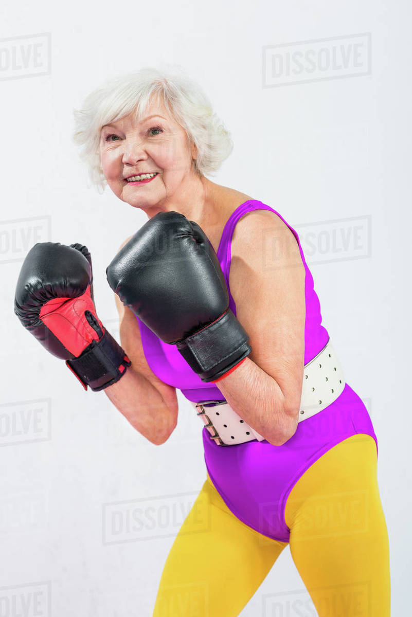 Portrait of beautiful sporty senior lady in boxing gloves smiling at