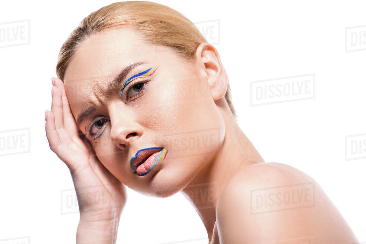 Irritated woman with colored makeup with lines looking at camera